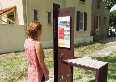 Visiteuse intéressée par le panneau d'information "Le casernement" de l'association "Echappées salinières" 